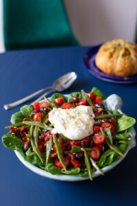 Snijbonensalade met tomaat en burrata met brood op de achtergrond