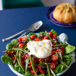 Snijbonensalade met tomaat en burrata met brood op de achtergrond