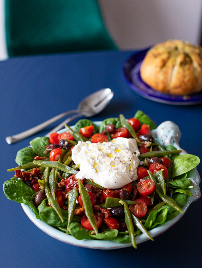 Snijbonensalade met tomaat en burrata met brood op de achtergrond